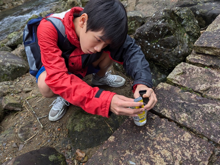 學生在烏塗溪進行水質酸鹼度量測